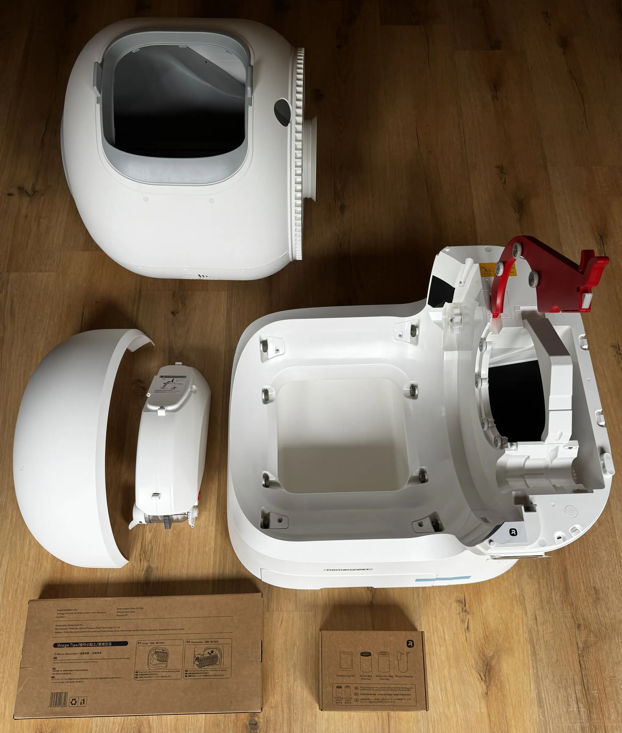 Top-down unboxing view of the homerunPET CS106 with the dome, base, reservoir, and accessory boxes laid out before setup